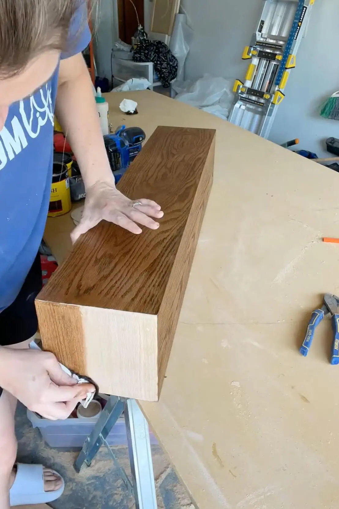 Applying stain to a DIY oak fireplace mantel to achieve a warm, rich finish.